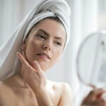 Selective Focus Portrait Photo of Woman With a Towel on Head Looking in the Mirror